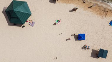 Havadan izlenen şemsiyeler ve güneşlenen insanlar Granbury, Teksas 'taki City Beach Park' ta plaj aktivitelerinin keyfini çıkarıyorlar. Güneşli bir günde umumi kumlu sahil şeridi aile pikniği eğlencesi ile rahatla