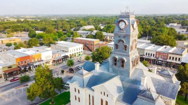 ABD 'nin Teksas, Granbury şehir merkezindeki tarihi Hood County Adliyesi Saat Kulesi' ne yakın çekim. Shanley Park ve yerleşim alanından yeşil sokak yatay arka planı