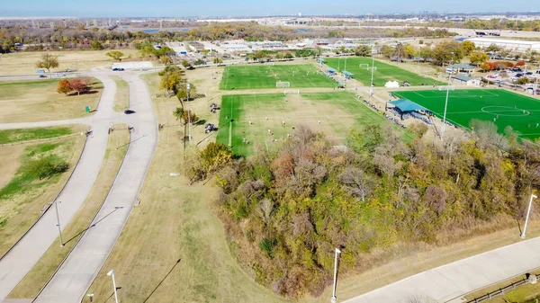 テキサス州ダラス近郊の工業倉庫地区を背景に スポーツ複合施設でのサッカートーナメントイベントをご覧ください 郊外のスポーツパーク施設で天然の人工のフィールドでのユースサッカーチーム — ストック写真