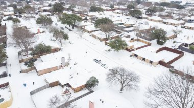 Dallas, Teksas, ABD yakınlarındaki mahalle caddesinde bulunan evleri ve arabaları hava manzaralı yoğun kar kapladı. Kar fırtınasından sonra büyük arka bahçeli banliyö evleri ayrıldı