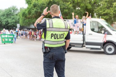 Vatandaş, Dallas, Teksas, Amerika yakınlarındaki 4 Temmuz geçit töreni sokak etkinliğinde polis memuruyla el sallıyor. Festivalde kolluk kuvvetleri ve güvenlik görevlisi.