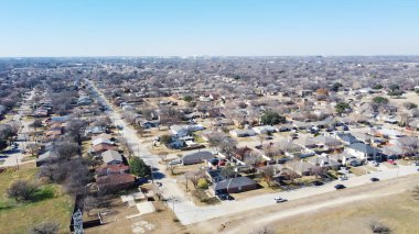 Dallas, Teksas 'ın güneybatısındaki hava manzaralı banliyö mahallesi yatay çizgide. Sokağın ortasında ağaçlar ve arabalarla kışın banliyö evlerinin üzerinde uçuyorlar.