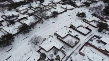 Dallas, Teksas, Amerika 'da yoğun kar banliyöleriyle kaplı yerleşim yeri caddesinde yürüyen sıcak ceketli yaşlı bayan. Kiremitli çatı, arka bahçe, dondurucu soğuk altında evler