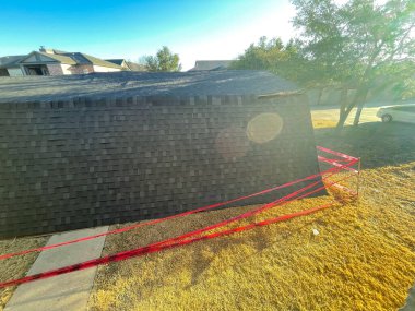 Dallas, Teksas, ABD banliyölerindeki hasarlı bir apartmanın çatı katı. Kırık çelik kaplama, sert hava koşulları ve kırmızı barikat bantlarıyla döşenmiş ticari garaj.