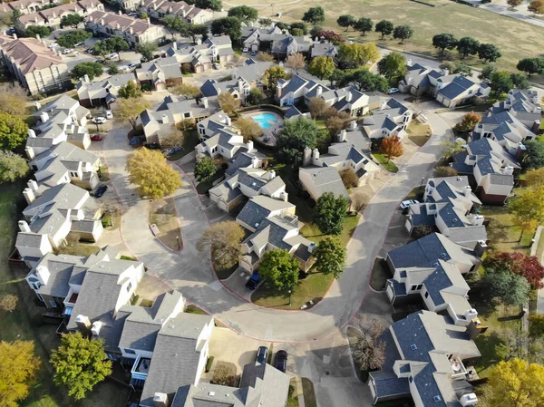 Üst manzara, Kuzey Teksas, Amerika 'da parlak sonbahar yeşillikleri olan büyük bir apartman kompleksinin yanında yüzme havuzu olan iki katlı yoğun şehir evi. Küçük arka bahçesi olan yerleşim evleri.