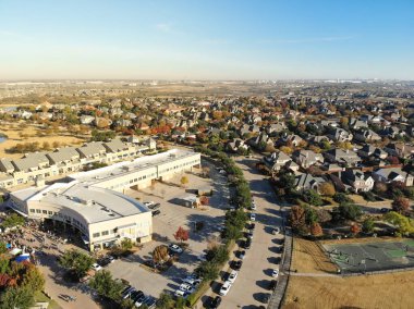 Dallas, Teksas, Amerika 'nın banliyölerinde halk etkinliği için toplanan insanların bulunduğu ticari binaların yanındaki en üst düzey yerleşim yerleri. Renkli sonbahar yapraklı iki katlı lüks evler.