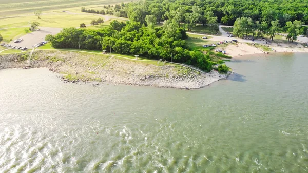 Top view Oklahoma side of Red River with strong water current generating from Denison Dam hydroelectric station and people bank fishing for striped bass. Spillway with parking space