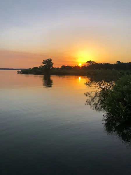 Early morning sunrise with calm water on Grapevine Lake, North Texas, America with trees in horizontal line. Early morning summertime fishing background.