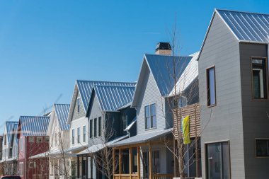 New development townhome with metal roof and covered gutters near Oklahoma City, US. Colorful urban style two story residential house with front porch cover and bay windows clear blue sky