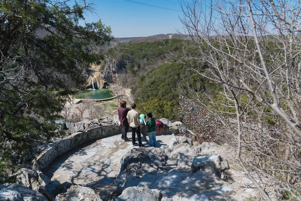 Rear view unidentified diverse people from viewpoint to Turner Falls on Honey Creek in the Arbuckle Mountains of south-central Oklahoma. A 77 feet waterfall considered OK state tallest waterfall