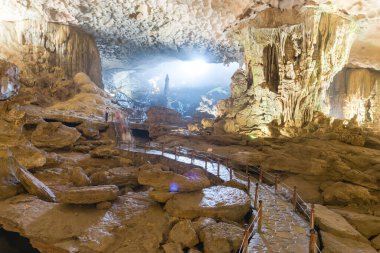 Stone pathway leading to the giant rock formation shaped like horse with a long-sword linked to the legend of Thanh Giong inside Sung Sot Cave Surprise Grotto in Ha Long Bay. Limestone caverns