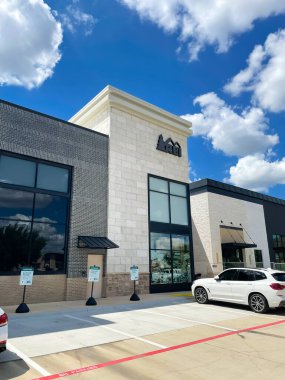 SOUTHLAKE, TX, US-AUG 28, 2022: Fa ade entrance to REI Recreational Equipment, Inc store with parked cars in front under sunny cloud blue sky. Retail and outdoor recreation services corporation