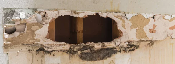 Panorama view broken drywall in bathroom with water damaged, mold, mildew on surface of residential house in Texas, US. Studs seen through hole of gypsum and cement board, plywood