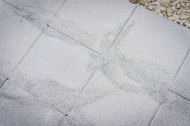 Teksas, ABD 'deki gri beton beton beton kaldırım taşı kaldırımının tepesinde polimerik kaldırım kumu. Yabani otları sıkılaştırmak ve önlemek için her kaldırım taşı, kiremit ya da doğal taş arasındaki eklem boşluklarını dolduracak malzeme