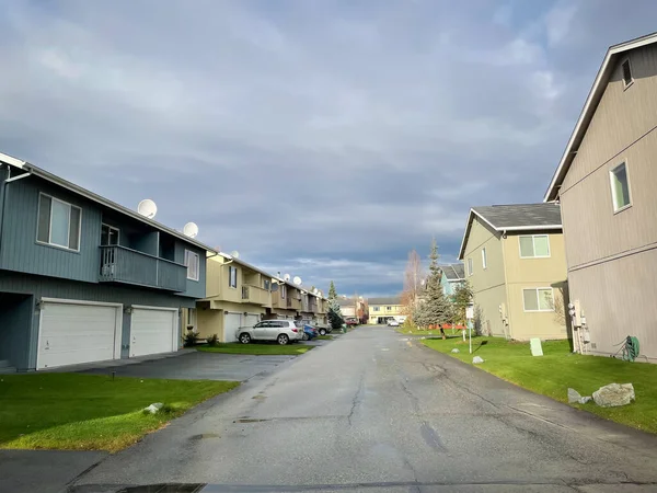 Row of two story duplex houses two units in the same building and share a common wall in Anchorage, Alaska. Multi-family home arranged side by side with large concrete pathway and curb appeal