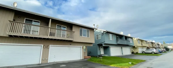 Panorama view two story duplex houses, two units in same building, share a common wall in Anchorage, Alaska. Multi-family home arranged side by side large concrete pathway curb appeal