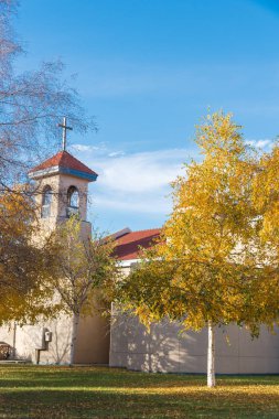 Katedral katedralinin çatısındaki haça bakıyorum. Beyaz Alaska huş ağaçları veya Betula neoalaskana 'nın parlak sarı yapraklarıyla Katolik Kilisesi inşa ediliyor. Anchorage, Alaska 'da kağıt huş ağacı veya reçine ağacı