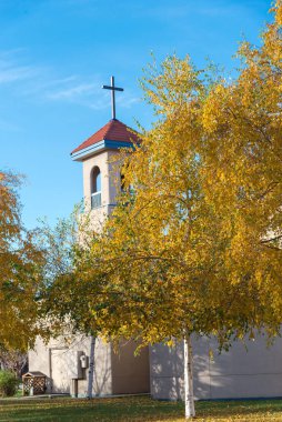 Katedral katedralinin çatısındaki haça bakıyorum. Beyaz Alaska huş ağaçları veya Betula neoalaskana 'nın parlak sarı yapraklarıyla Katolik Kilisesi inşa ediliyor. Anchorage, Alaska 'da kağıt huş ağacı veya reçine ağacı