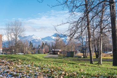 Çok katlı apartmanlara ve Anchorage 'daki Spenard Gölü yakınlarında Chugach Dağı' nın arka planında bulunan ticari binalara giden Hillside yolu. Yüzen uçaklar ve Ekim başında Alaska 'da manzara