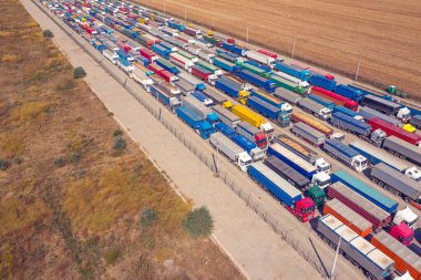 Liman terminali yakınındaki çok renkli kamyonlar yüklenmeyi ya da boşaltılmayı bekliyor. Modern lojistik merkezi. Hava görünümü.