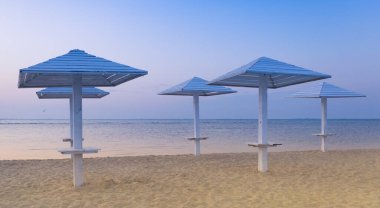 Adriyatik Denizi 'ndeki boş, temiz sahil. Güneş koruması için tahta şemsiyeler..