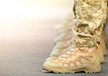Askerlerin bacakları ayak bileği botları ve kamuflaj pantolonu giymişti. Yakın çekim, seçici odaklanma.