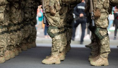 Askerlerin bacakları ayak bileği botları ve kamuflaj pantolonu giymişti. Yakın çekim, seçici odaklanma.