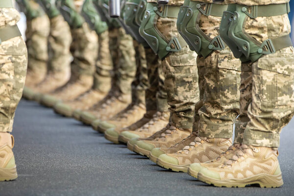 The soldiers' legs are dressed in ankle boots and camouflage pants. Close-up, selective focus.