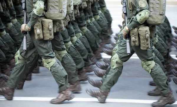 The soldiers\' legs are dressed in ankle boots and camouflage pants. Close-up, selective focus.