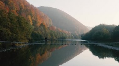 Sonbahar dağlarında nehrin üzerindeki ahşap asma köprü.