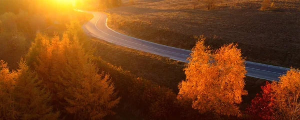 Verharde weg in de bergen. Herfstlandschap bij zonsondergang. — Stockfoto