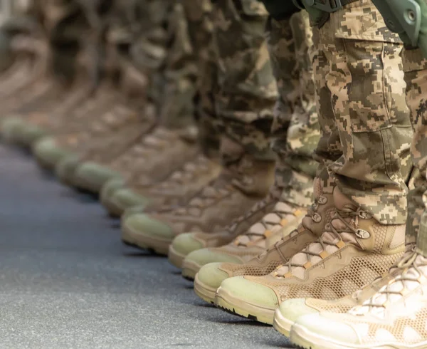 Las piernas de los soldados están vestidos con botas de tobillo y pantalones de camuflaje. Imagen De Stock