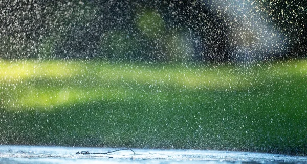 Капли дождя падают на асфальт и зеленую траву. — стоковое фото