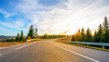 Dağlarda yüksek kalitede asfalt yol. Gün batımında işaretler ve yol altyapısı ile.