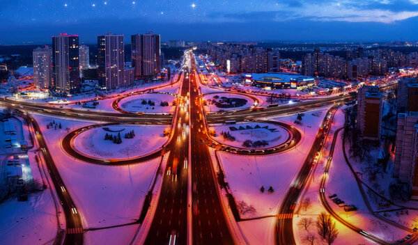 Top view, multilevel transport interchange in the evening city. Winter landscape.