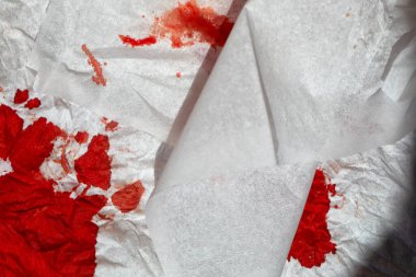 Fresh pink blood on a white paper napkin.
