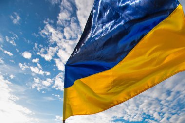 The flag of Ukraine on the background of the blue daytime sky.