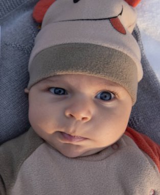 Pensive curious kid Portrait, close-up selective focus. The baby is dressed in autumn clothes and a hat.