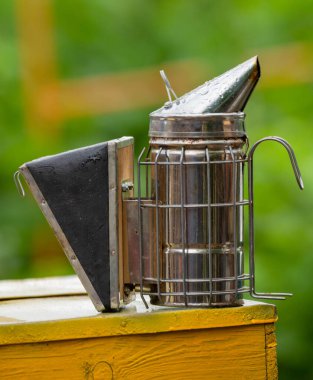 A beekeeper's chimney stands on a beehive, selective focus, a beekeeper's tool for bee care.