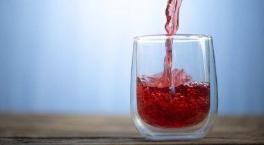 Kırmızı sıvı, meyve suyu ya da şarap bardağa dökülür..