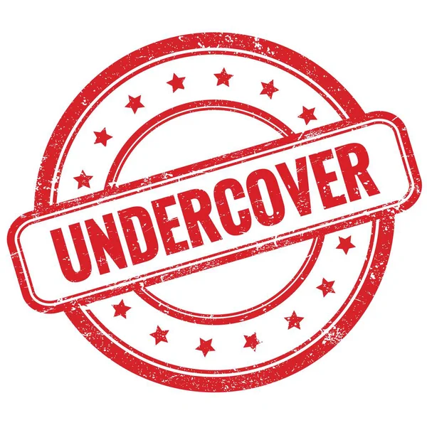 UNDERCOVER 'un kırmızı, eski, pasaklı, yuvarlak, lastik damgalı metni.