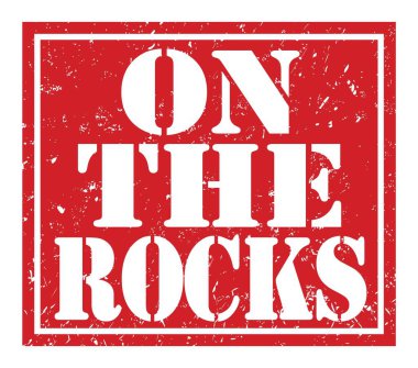 Kayaların üzerinde, kırmızı damga işareti üzerine yazılmış kelimeler.