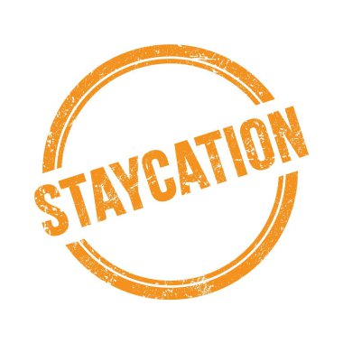 STAYCATION metni turuncu grungy vintage yuvarlak pul üzerine yazılmış.