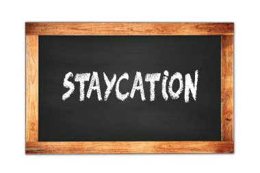 STAYCATION text written on black wooden frame school blackboard.