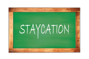 STAYCATION metni yeşil ahşap çerçeve okul tahtasına yazılmış.
