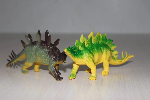 Two Stegosaurus toy dinosaurs on white  background