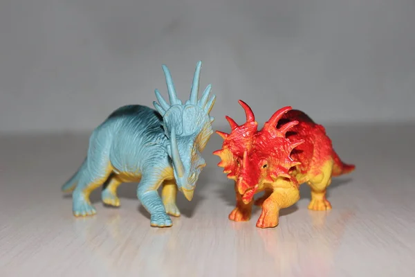 Two Triceratops toy dinosaurs on white background