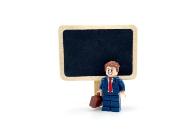 A businessman standing in front of blackboard. Lego figure photography concept idea.