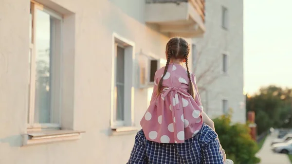 Papá juega con su hija, camina por la calle de la ciudad con su hijo amado. Niño y padre. Padre camina con su hija sobre sus hombros en un parque de verano. Una familia feliz. Fin de semana familiar al aire libre —  Fotos de Stock