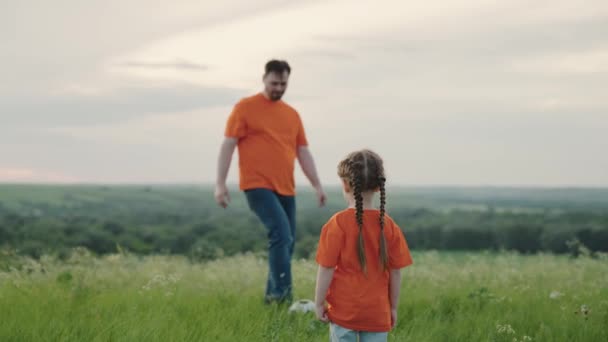 Father, daughter, child cheerfully play ball on lawn in park. Young family sports soccer team playing outdoors. Happy family playing soccer, soccer ball. Kid learns to play soccer ball — Stock Video